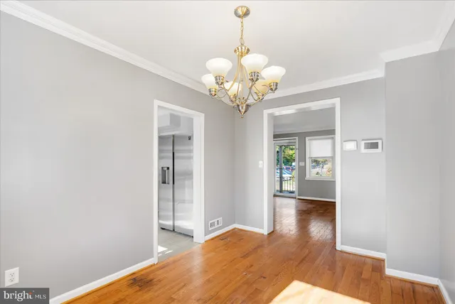 a view of a hallway with wooden floor and chandelier