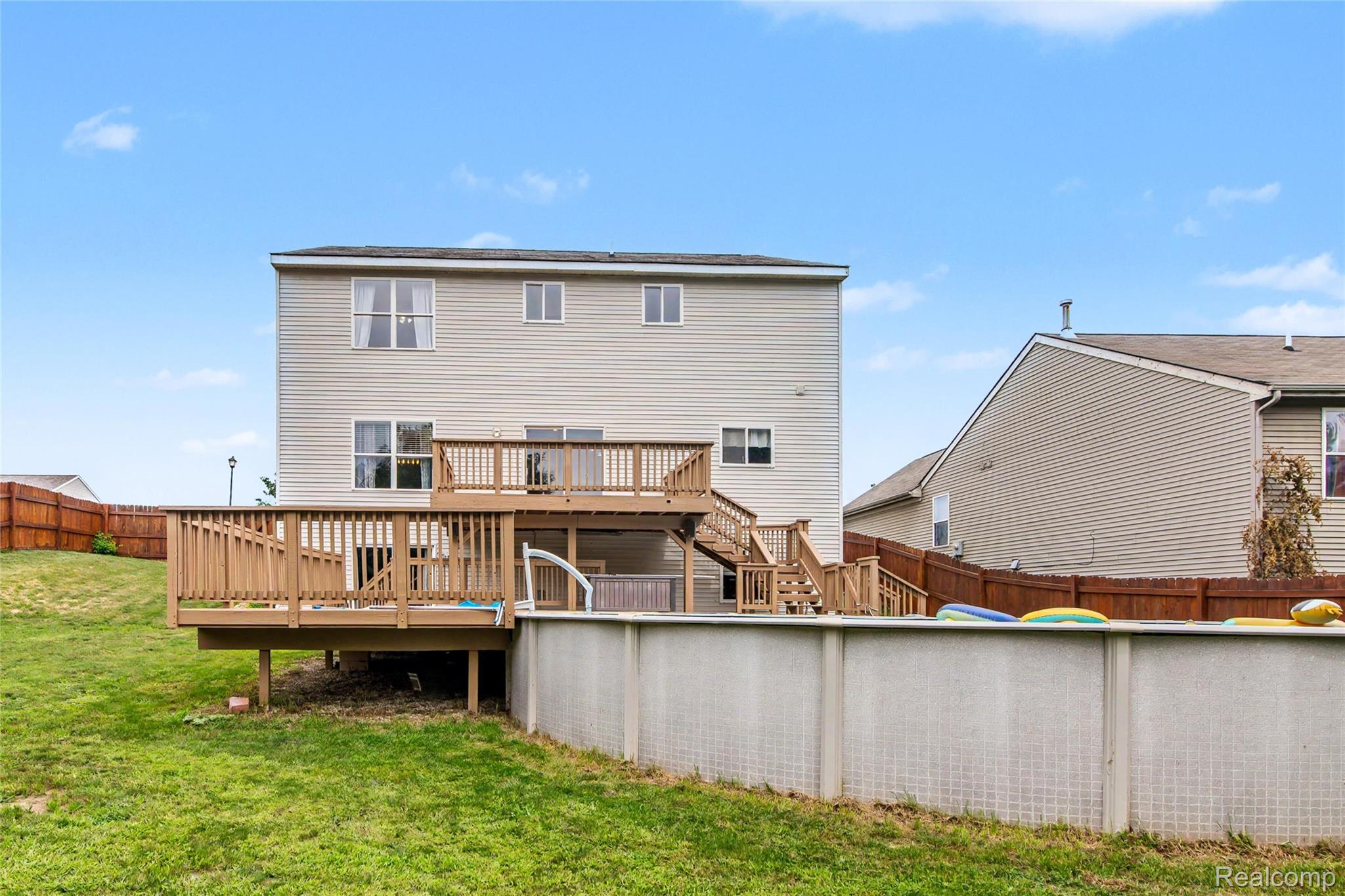 486 Sweet Briar Ridge Linden, MI 48451 - Photo 6 of 69 Expansive backyard featuring a multi-level wood deck, an above-ground swimming pool, and a sloped grass lawn