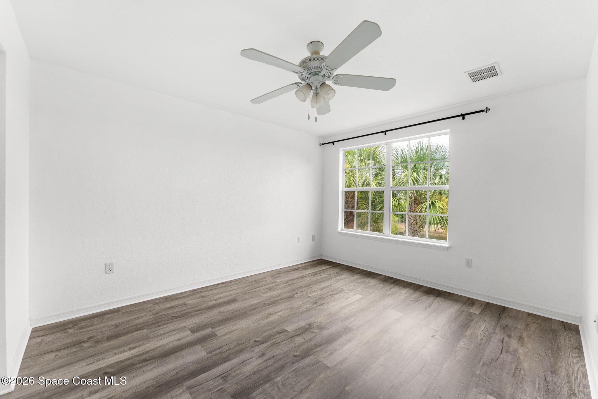 110 Turpial Way, Unit 106 Melbourne, FL 32901 - Photo 27 of 50 an empty room with wooden floor fan and windows
