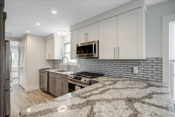 a kitchen with granite countertop a stove sink and microwave