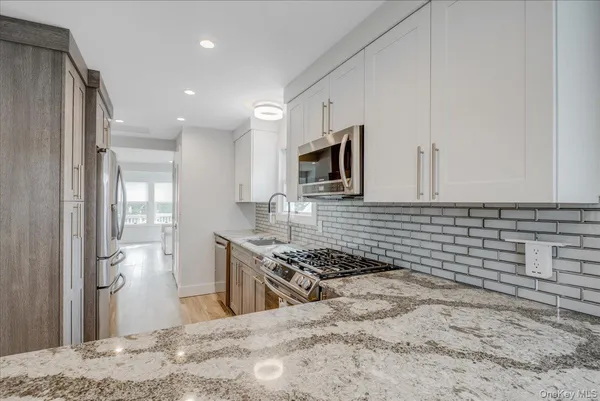 a kitchen with granite countertop a sink stove and refrigerator