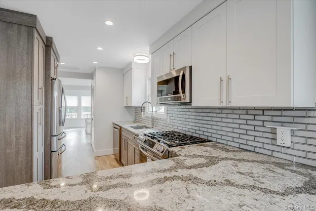 a kitchen with granite countertop a sink stove and refrigerator
