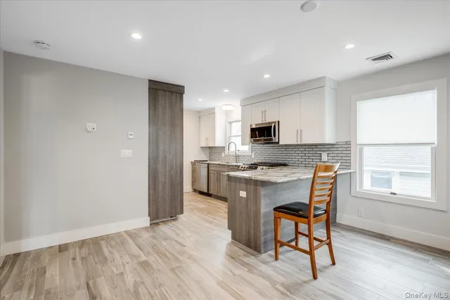 a kitchen with stainless steel appliances granite countertop a stove a sink a refrigerator with a dining table and chairs