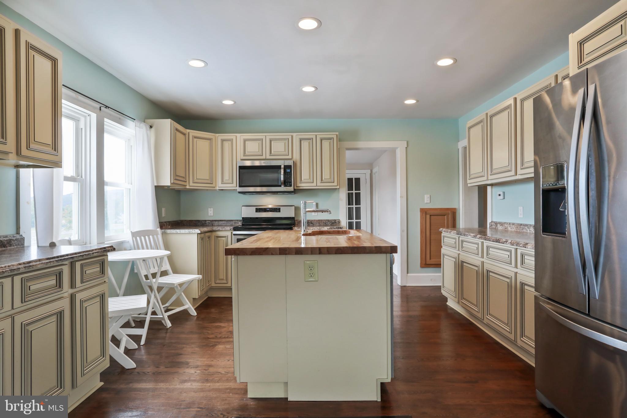 217 Poorhouse Road Winchester, VA 22603 - Photo 9 of 39 a kitchen with stainless steel appliances granite countertop a refrigerator a stove top oven a sink dishwasher and white cabinets with wooden floor