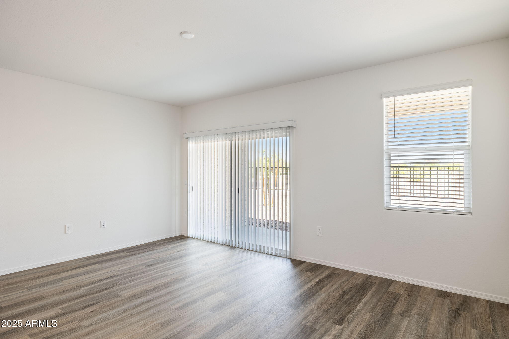 18401 West Hackamore Drive Wittmann, AZ 85361 - Photo 12 of 22 an empty room with wooden floor and windows