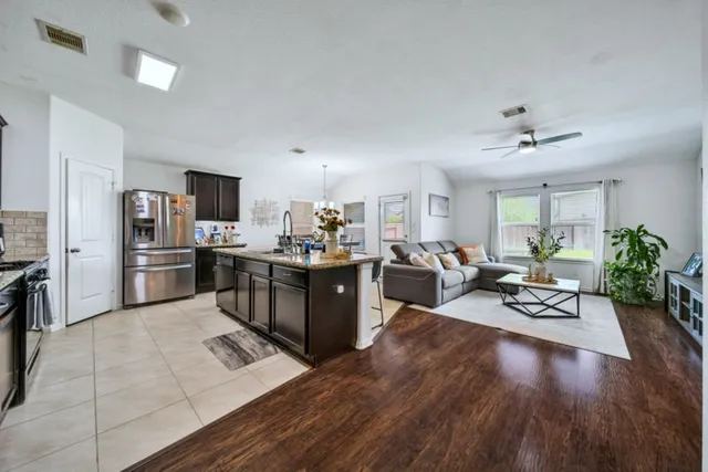 a living room with furniture kitchen view and a wooden floor
