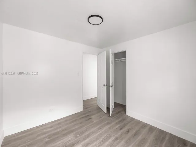 a view of an empty room with wooden floor and glass door