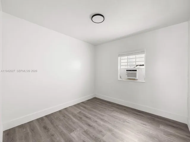 a view of a room that has wooden floor and window