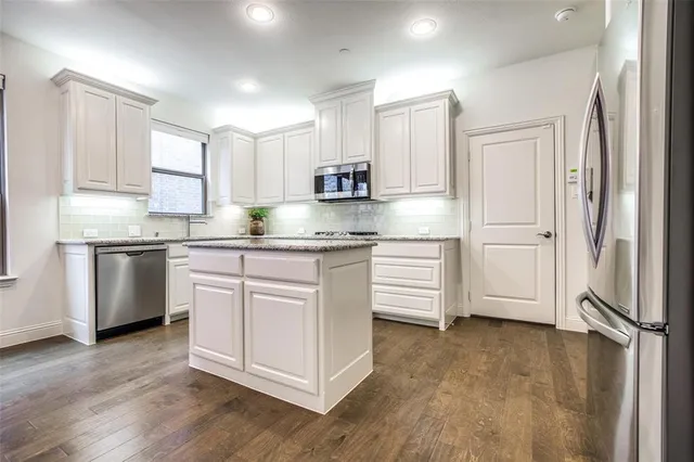 a kitchen with stainless steel appliances granite countertop a refrigerator sink and white cabinets
