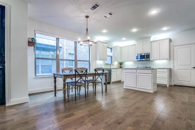a kitchen with stainless steel appliances a dining table chairs stove and white cabinets
