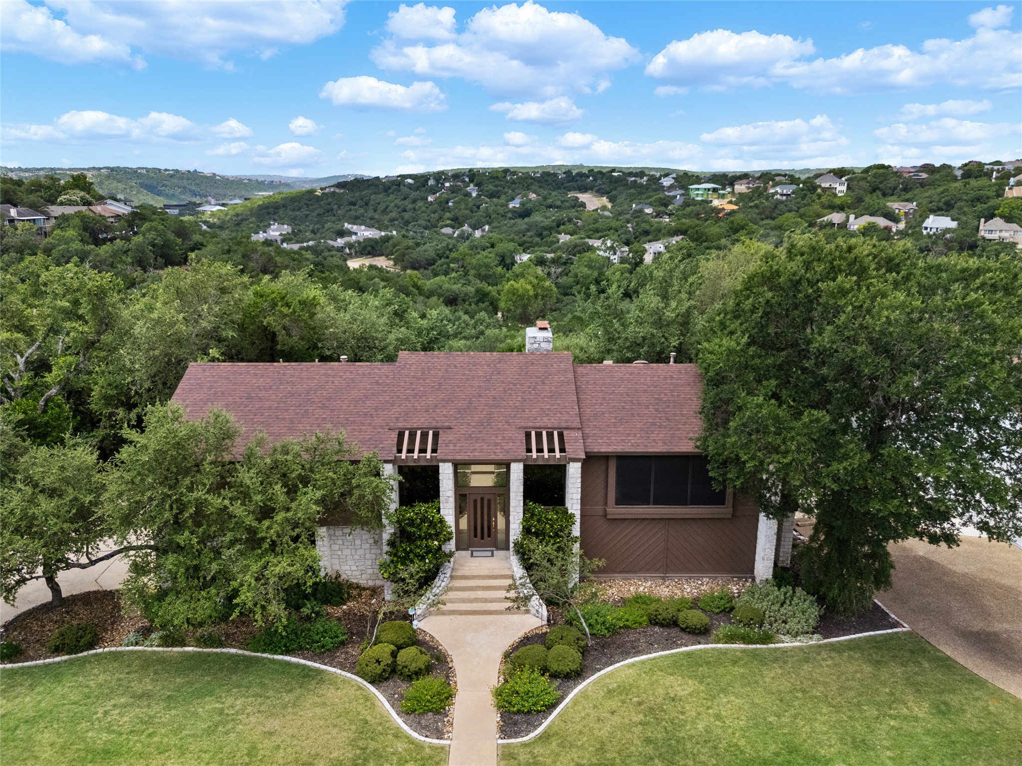 5319 Musket Ridge Austin, TX 78759 - Photo 3 of 39 A captivating residence features an appealing blend of stone and wood siding, complemented by a neatly manicured lawn and mature landscaping.