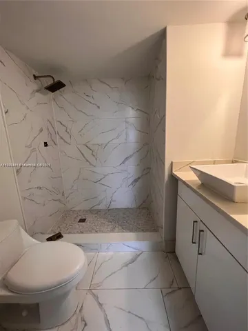a bathroom with a granite countertop toilet and a sink