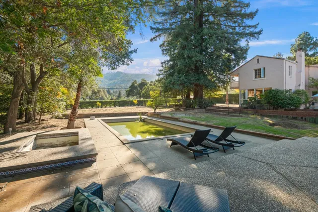 a view of a swimming pool with lounge chair in front of house