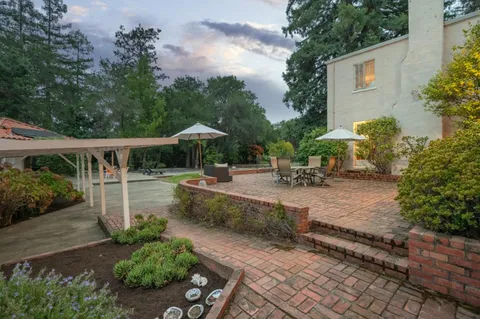 a view of a patio with table and chairs potted plants with large tree