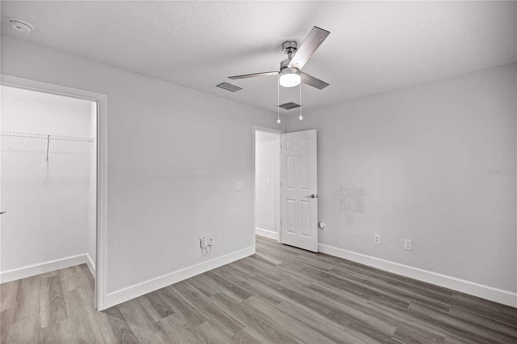 8607 Southwest 135th Street Road Ocala, FL 34473 - Photo 13 of 30 an empty room with wooden floor fan and windows