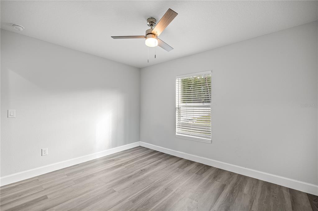 8607 Southwest 135th Street Road Ocala, FL 34473 - Photo 14 of 30 an empty room with wooden floor chandelier fan and windows