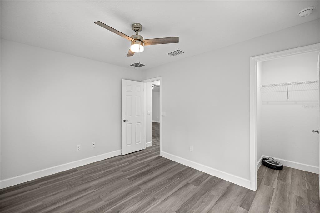 8607 Southwest 135th Street Road Ocala, FL 34473 - Photo 17 of 30 an empty room with wooden floor ceiling fan and window