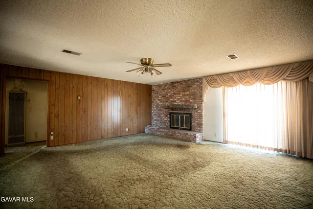 an empty room with windows and fireplace