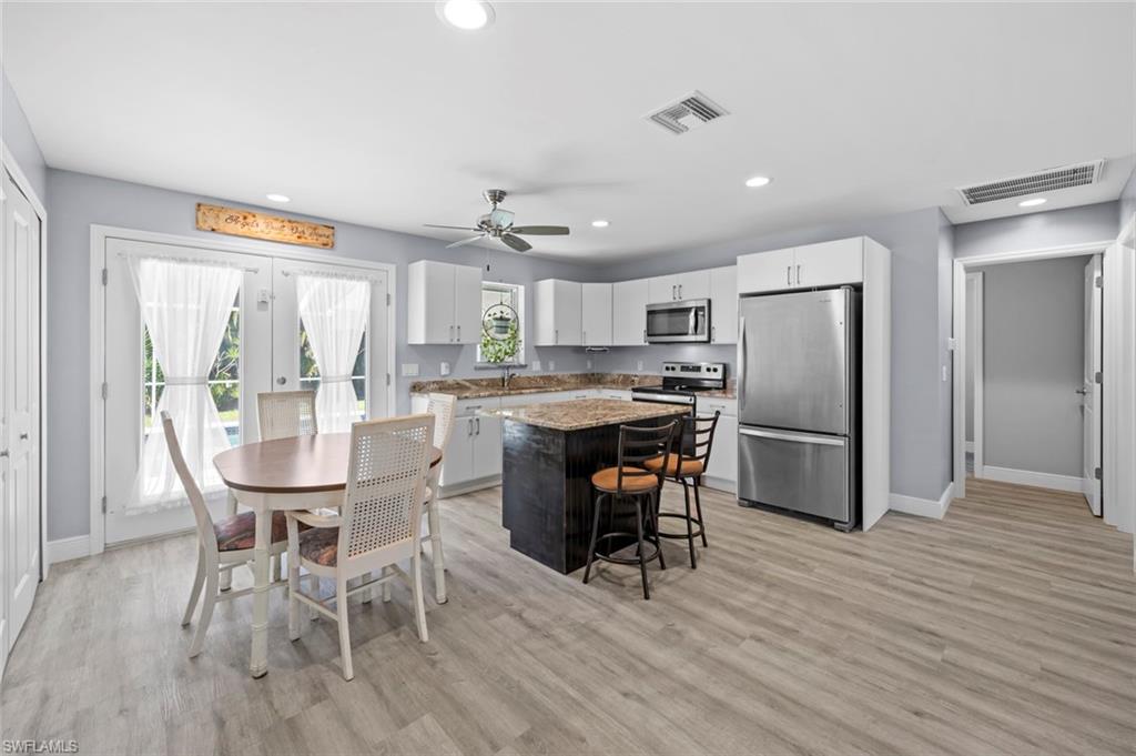 17528 Fuchsia Road Fort Myers, FL 33967 - Photo 3 of 42 a kitchen with stainless steel appliances a dining table chairs refrigerator and cabinets
