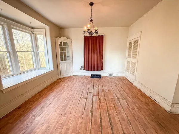 a view of a room with wooden floor chandeliers and kitchen view