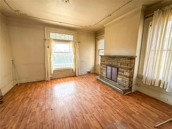 an empty room with wooden floor fireplace and windows