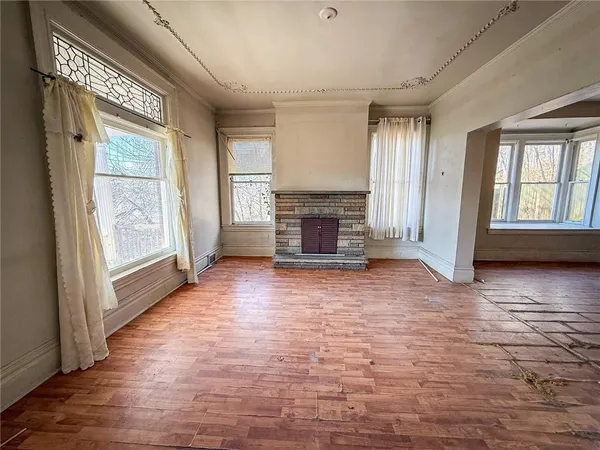 an empty room with windows fireplace and wooden floor