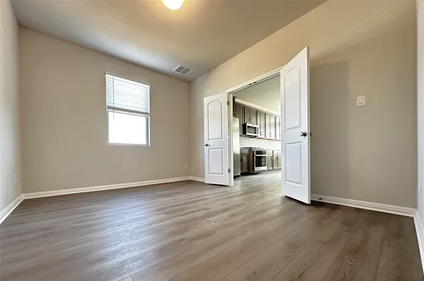 an empty room with wooden floor fireplace and windows