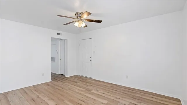 an empty room with a ceiling fan and window