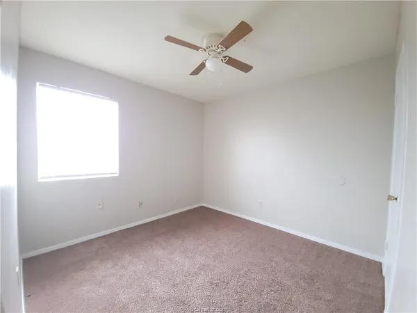 an empty room with a window and ceiling fan