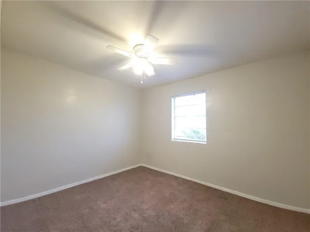 an empty room with a window and ceiling fan