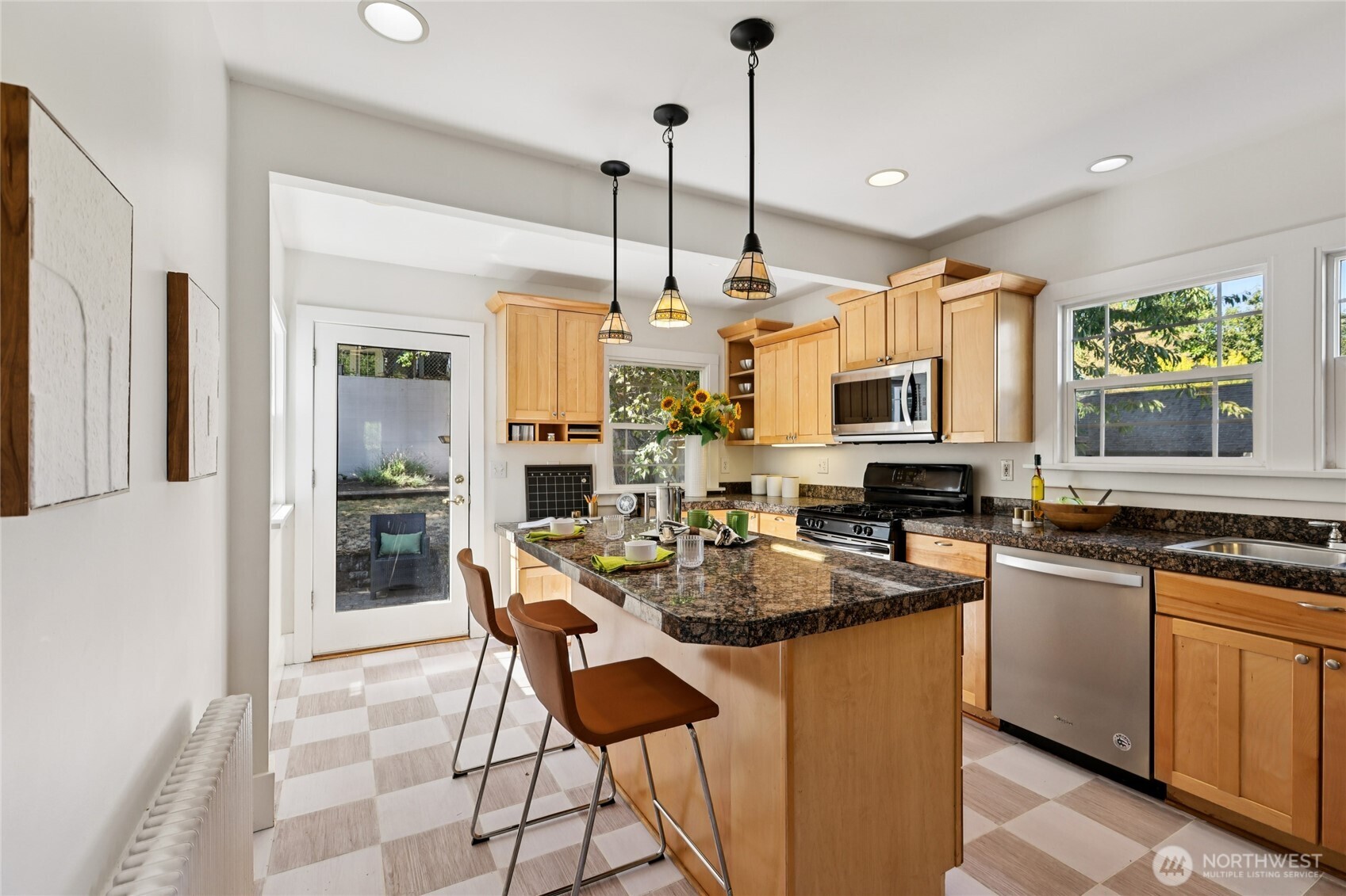511 23rd Avenue East Seattle, WA 98112 - Photo 12 of 39 a kitchen with stainless steel appliances kitchen island granite countertop a stove a refrigerator a sink a dining table and chairs with wooden floor