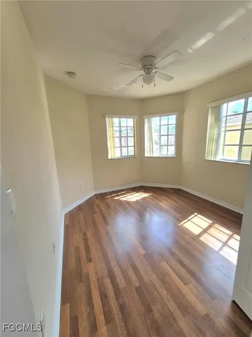 a view of empty room with wooden floor and fan