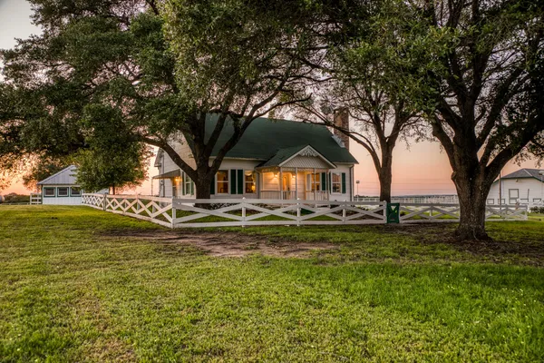 a view of swimming pool with lawn chairs and large trees