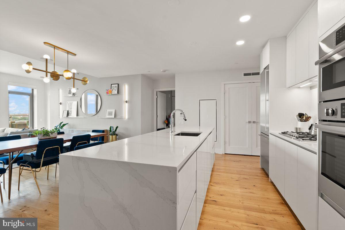 1211 Van Street Southeast, Unit PH13B Washington, DC 20003 - Photo 5 of 25 a large white kitchen with cabinets a sink a window and stainless steel appliances