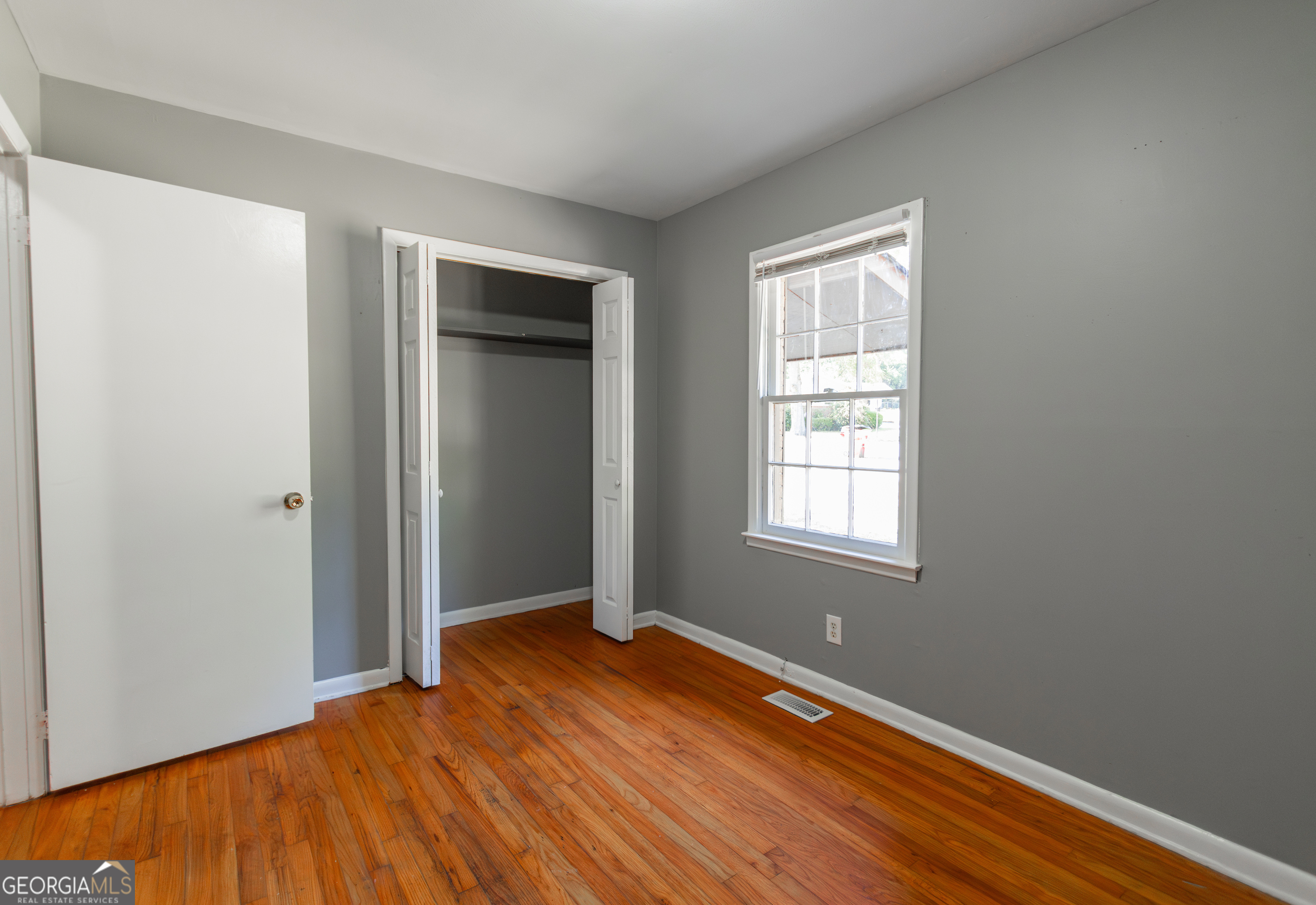 208 Bassett Street Centerville, GA 31028 - Photo 14 of 24 a view of an empty room with wooden floor and a window