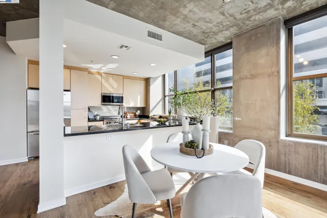 a kitchen with stainless steel appliances granite countertop a dining table chairs and a refrigerator