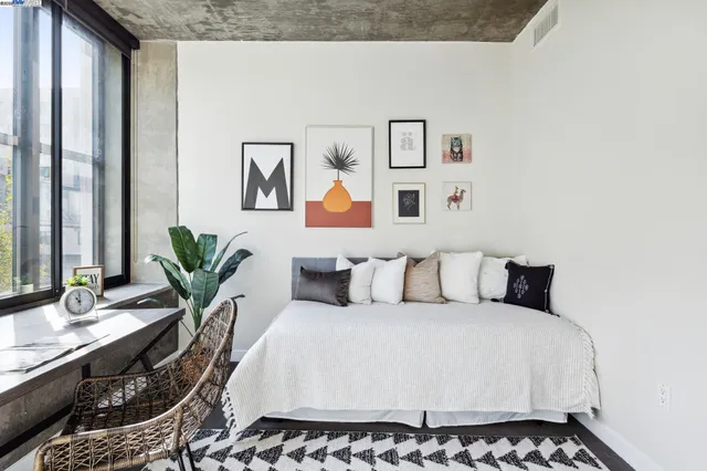 a bedroom with a large bed and a potted plant on a dresser
