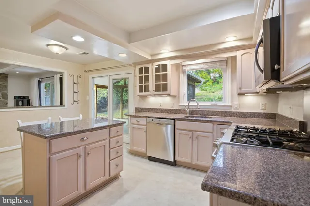 a kitchen with kitchen island granite countertop a sink stove and cabinets