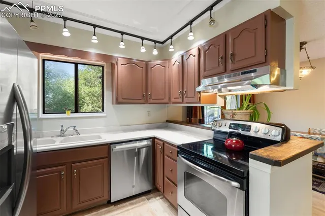 a kitchen with stainless steel appliances granite countertop a sink a stove and a refrigerator