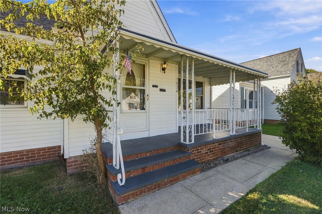 1434 Sunset Road Mayfield Heights, OH 44124 - Photo 13 of 36 Covered front porch with decorative metal railings, brick foundation, and concrete steps