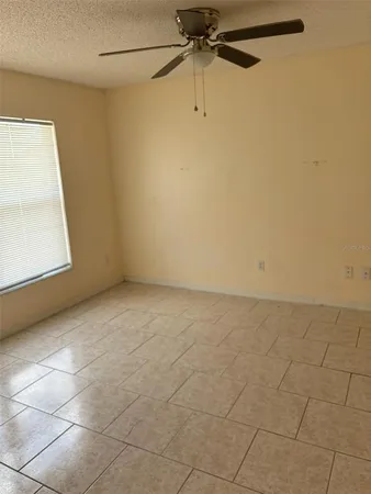 an empty room with a window and a fan