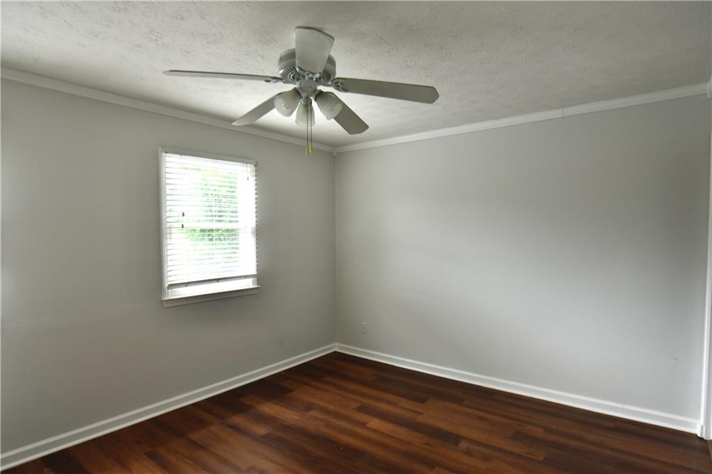 2898 Webb Bridge Road Alpharetta, GA 30009 - Photo 5 of 8 an empty room with wooden floor fan and windows