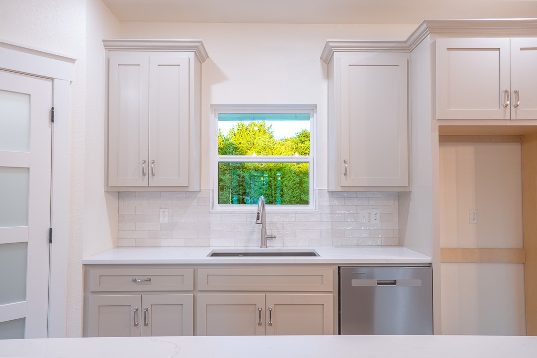 205 Blessings Way Colbert, OK 74733 - Photo 13 of 24 Kitchen featuring light-toned cabinetry with crown molding, stainless steel sink, and a stainless steel dishwasher