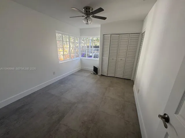 en empty room with windows and ceiling fan