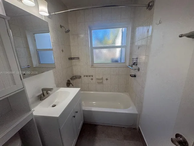 a bathroom with a tub sink and mirror