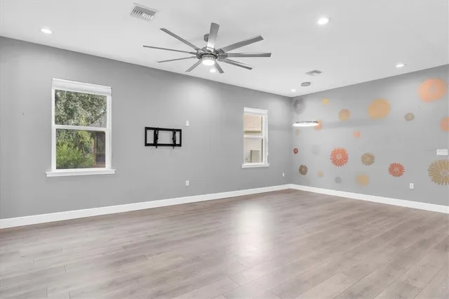 a view of an empty room with wooden floor and a window