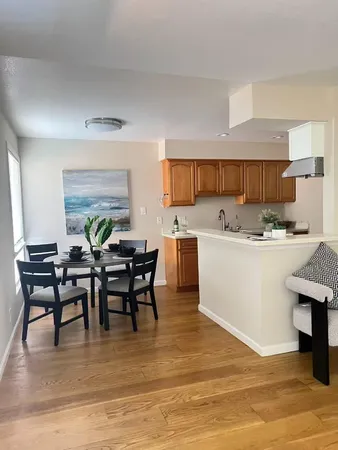 a living room with stainless steel appliances kitchen island a table chairs and a refrigerator