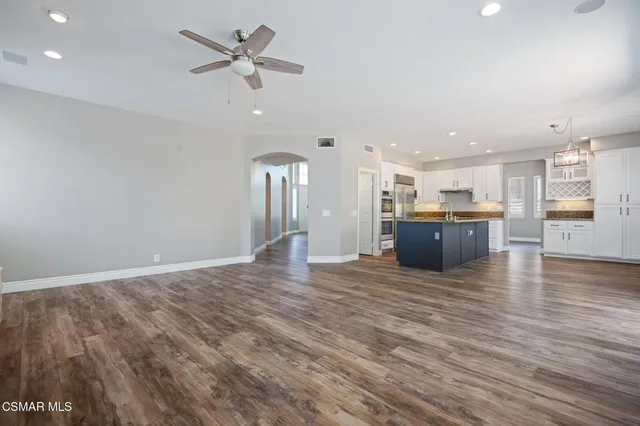 a view of a big room with wooden floor and a kitchen
