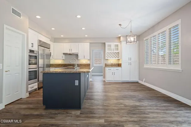 a kitchen with stainless steel appliances granite countertop a refrigerator a sink dishwasher and a stove with wooden floor