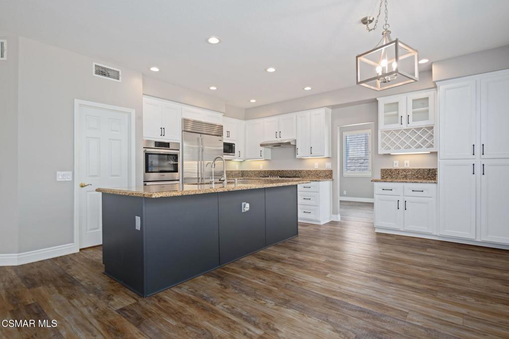 335 Kitetail Street Simi Valley, CA 93065 - Photo 15 of 55 a kitchen with stainless steel appliances granite countertop a refrigerator a sink dishwasher a stove and white countertops with wooden floor